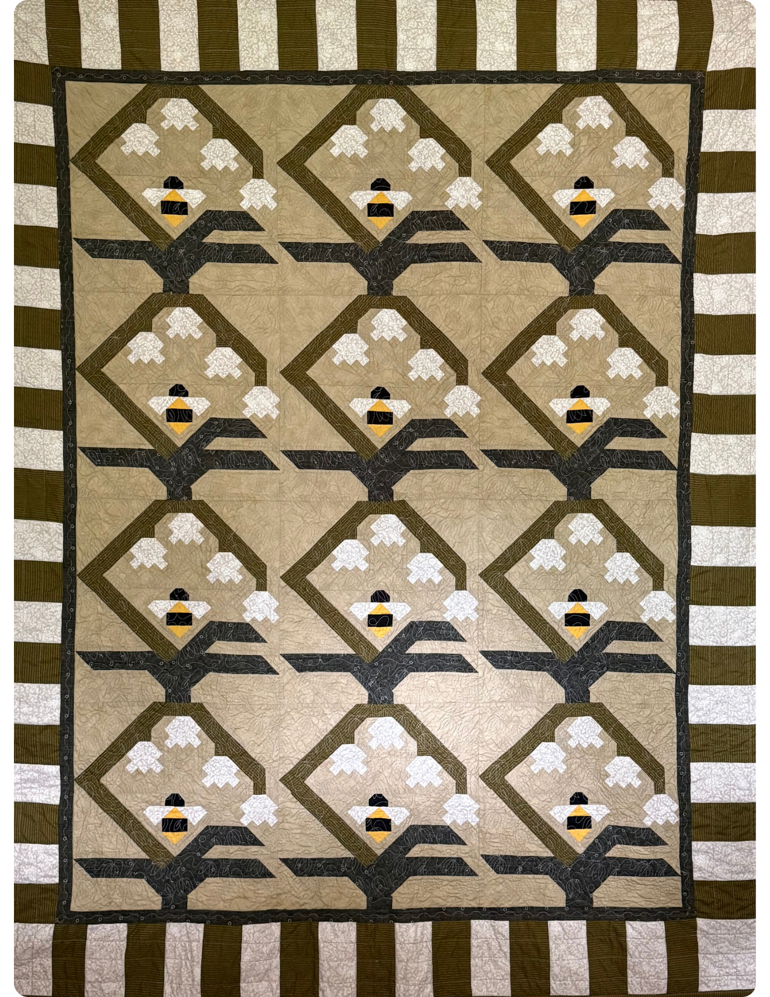 Full view of quilt with green and white stripe border. 3x4 flower and bee quilt block in the center.