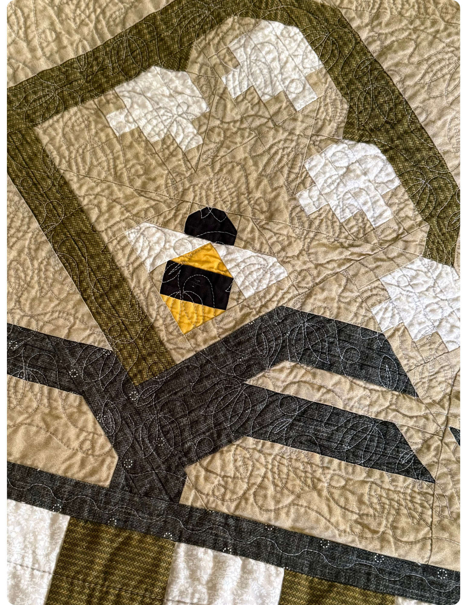 Close up of quilt with green and white stripe border. Flower and bee quilt block.